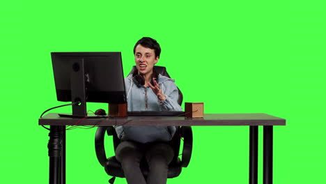 Young-woman-playing-video-games-online-on-pc-at-desk-against-greenscreen